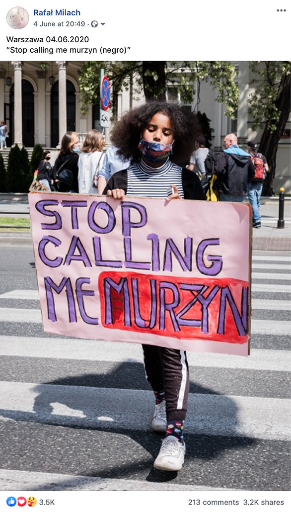 Zdjęcie. Dziewczynka niesie różowy transparent z napisem "Stop calling me murzyn"